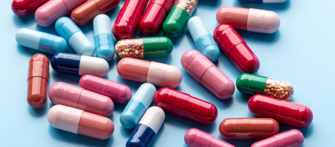 Colorful different medicine capsules on blue background