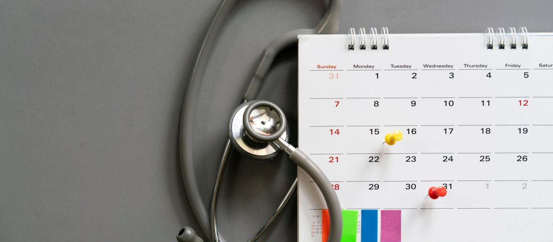 Top view of stethoscope and calendar on the gray background, schedule to check up healthy concept