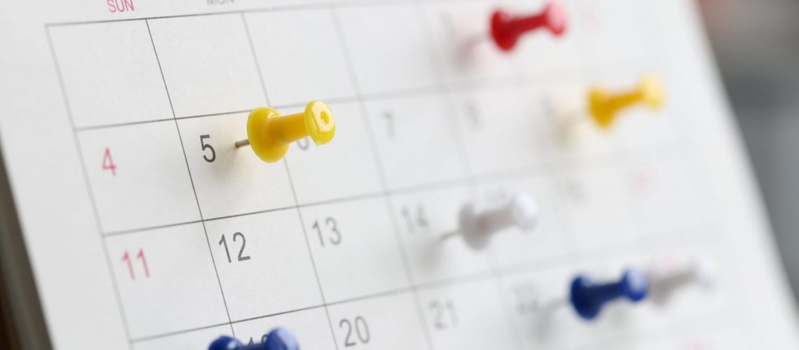 Various color thumb tack pins on calendar as reminder. Important business days concept