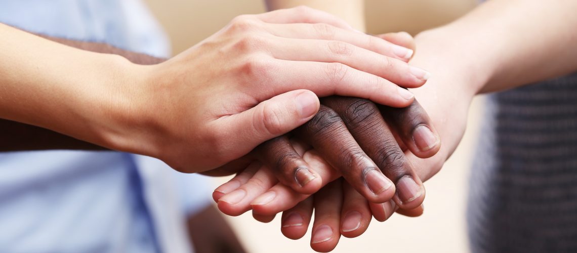 White caucasian and black afro american hands holding together, friendship concept